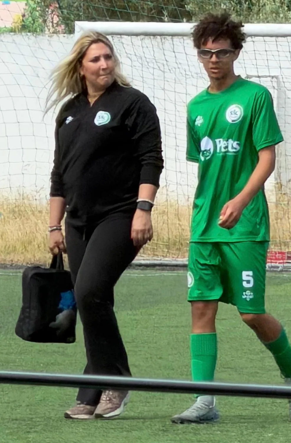 A Helena no relvado, ao lado de um jogador, com a mala de primeiros socorros na mão