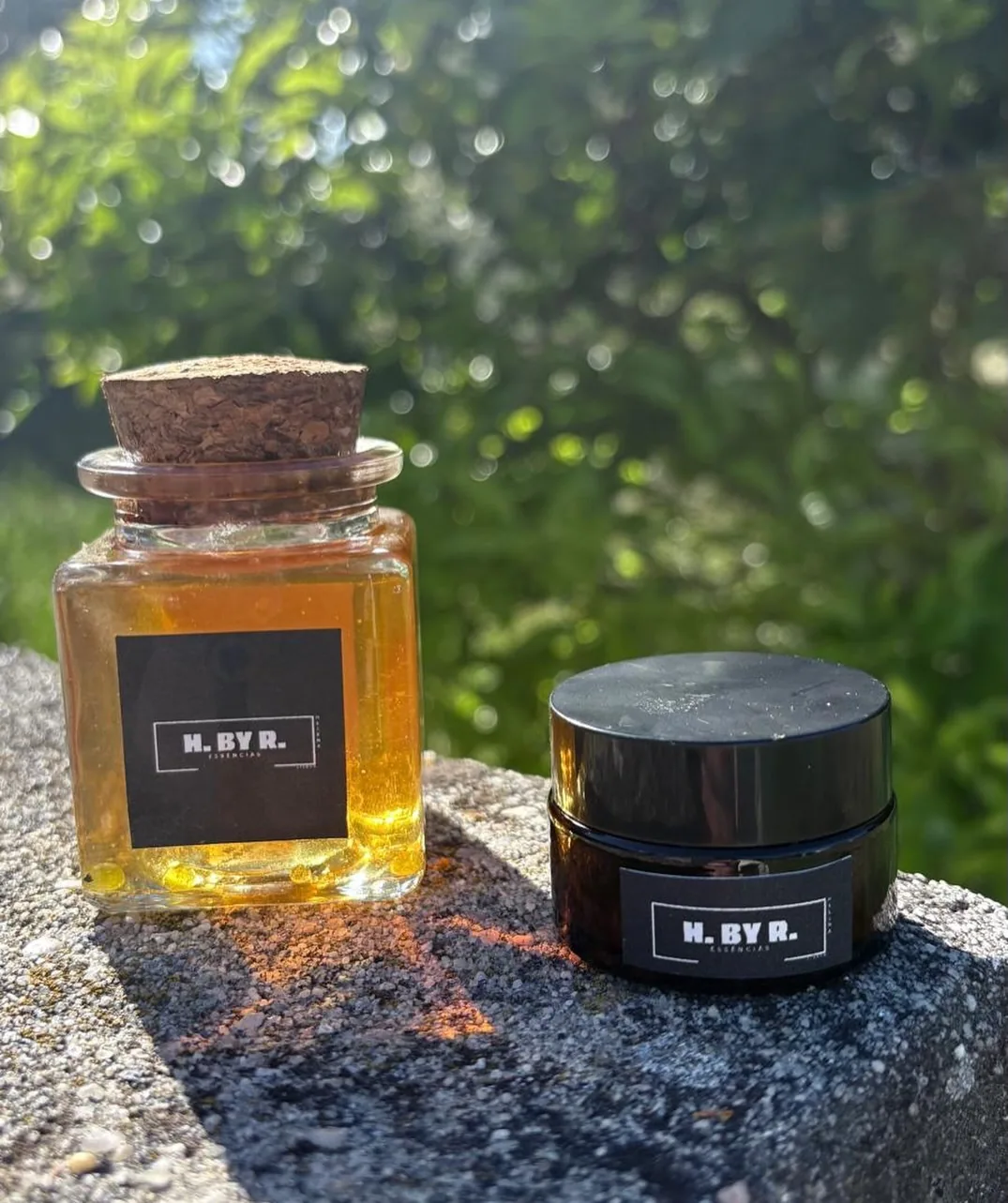 H.By.R essence bottle with a cork stopper and a jar of therapeutic cream, in the sun